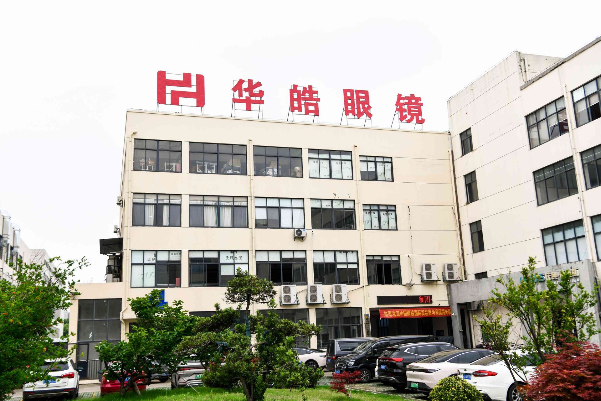 Fachada de la fábrica de HAO Eyewear con entorno ajardinado en Danyang