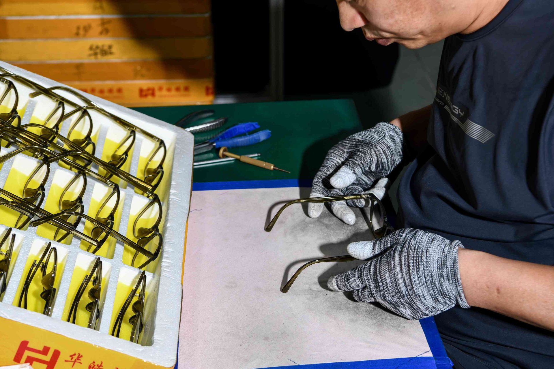 Close-up of a gloved worker inspecting an eyewear frame during assembly at HAO Eyewear