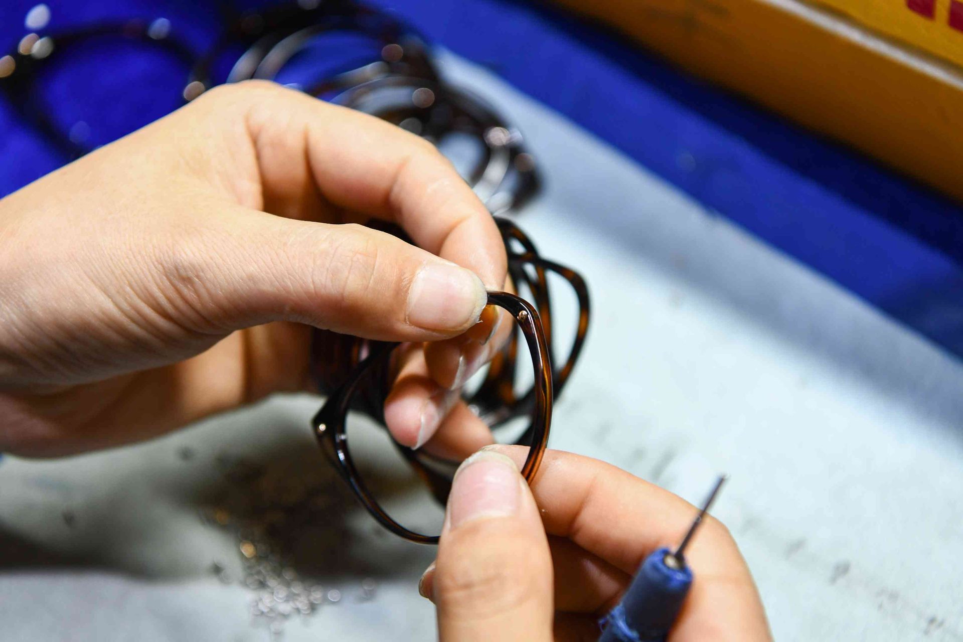 Hand assembly of a tortoiseshell acetate eyewear frame with precision screws at HAO Eyewear