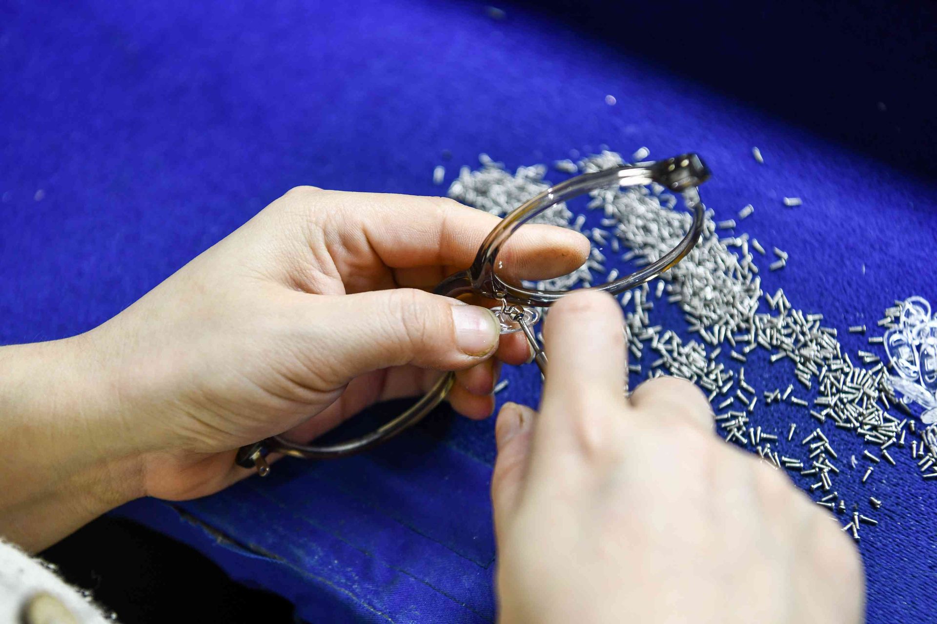 Arbeiter setzt Mikro-Scharnierschrauben in eine Metallfassung bei HAO Eyewear ein