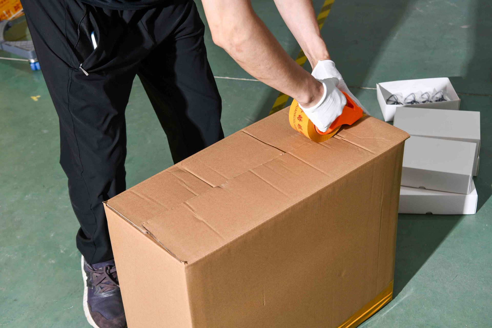 Worker taping a shipping carton of eyewear ready for global export at HAO Eyewear