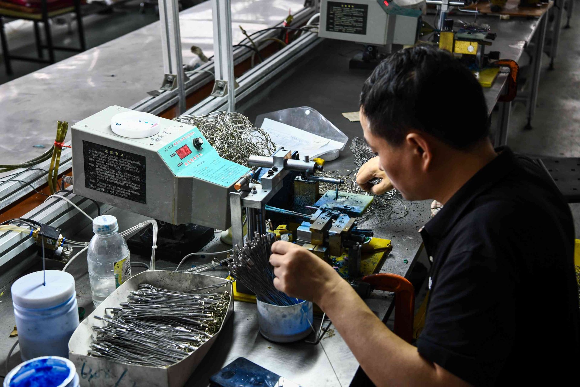 Technician joining metal eyewear frame components in a production workshop